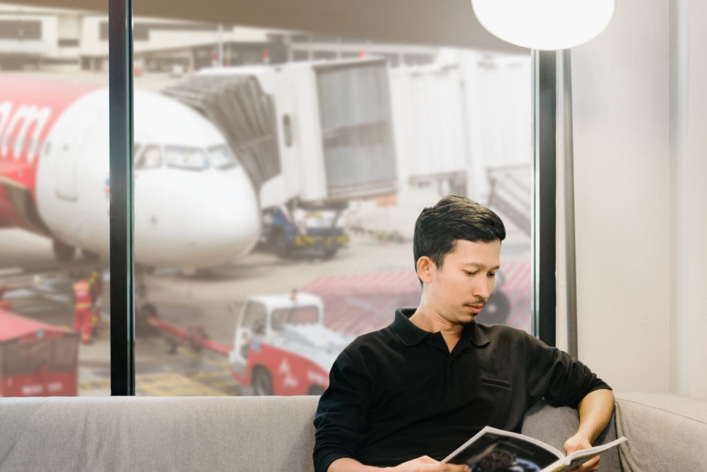 Asian man reading a magazine in the lounge at the airport in selective focus.